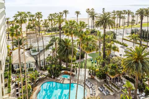 Aerial view of resort with turquoise pool surrounded by palm trees and ocean in background