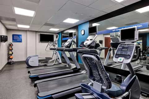 Fitness center with treadmills, exercise equipment, and blue accent wall accents