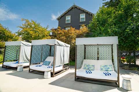 Outdoor spa area with two white canopy daybeds with blue patterned cushions near historic building
