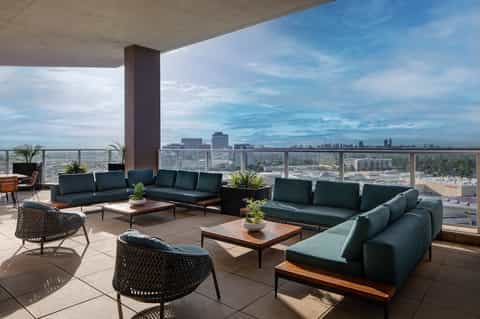 High-rise hotel terrace with modern green seating, city skyline views, and contemporary furnishings