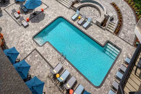 Resort swimming pool surrounded by lounge chairs and blue umbrellas