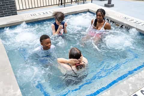 Children enjoying a hot tub with jets and bubbling water on rooftop deck