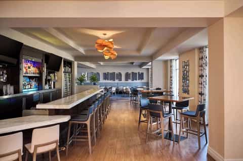 Upscale hotel bar and lounge with stone counters, backlit shelving, and ocean-view windows