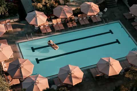 Lap pool with pink umbrellas and lounge chairs viewed from above at sunset