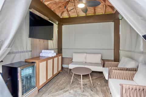 Glamping tent interior with comfortable seating, entertainment system, and modern amenities