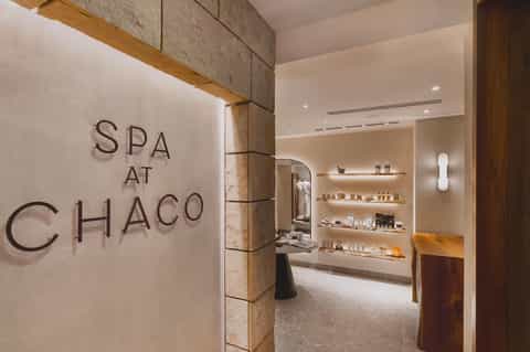 Spa entrance with stone accents, timber beam details, and illuminated shelving displaying spa products