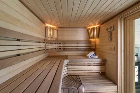 Wooden sauna interior with benches, warm lighting, and contemporary design elements