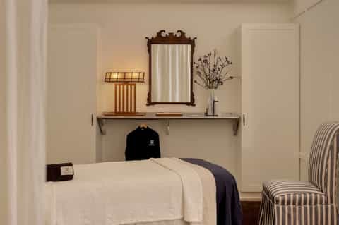 Minimalist spa treatment room with white bed and wooden mirror frame