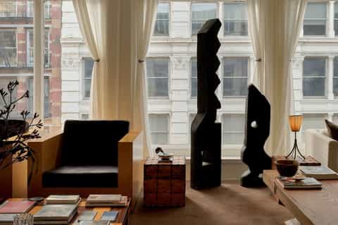 Upscale hotel lounge with black sculptural art, city windows, and contemporary furnishings