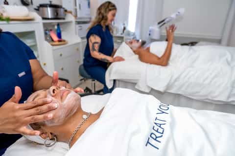 Spa therapist applying treatment to guest's hand in modern wellness treatment room