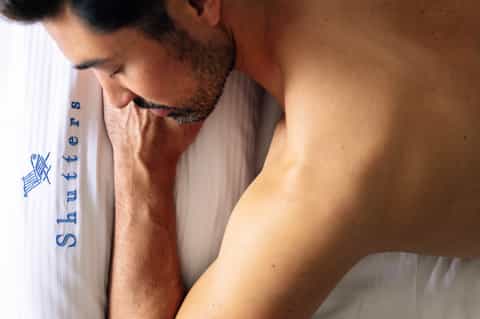 Man wearing white towel with blue resort branding, showing shoulder detail