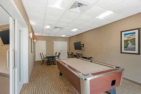 Game room with pool table, meeting area with table and chairs, and flat-screen TV