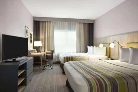 Hotel room with two queen beds, striped bedding, work desk, and warm neutral color scheme
