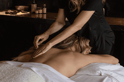 Professional spa therapist performing back massage on relaxed client in treatment room