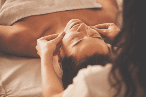 Person receiving professional facial massage treatment on massage table