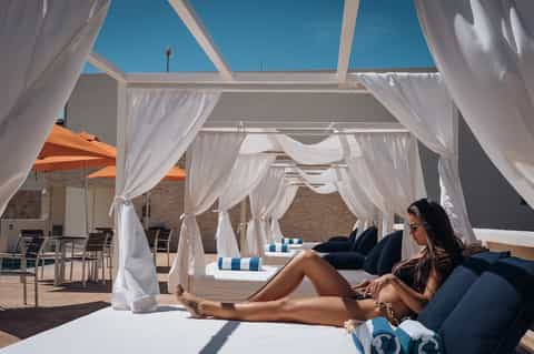Resort daybed cabanas with white curtains, striped loungers, and ocean views
