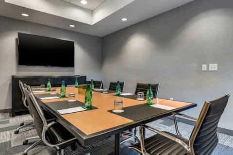 Conference room with wooden table, office chairs, TV monitor, and gray walls