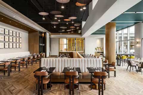Modern hotel restaurant interior with white banquettes, wood furnishings, and contemporary lighting