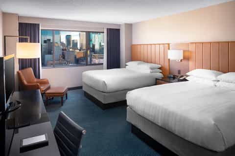 Hotel room with two beds, orange headboards, and city skyline views