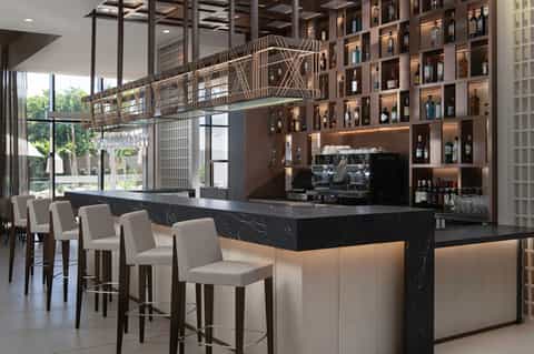 Contemporary hotel bar with black marble counter, wine shelves, brass lighting, and lounge seating