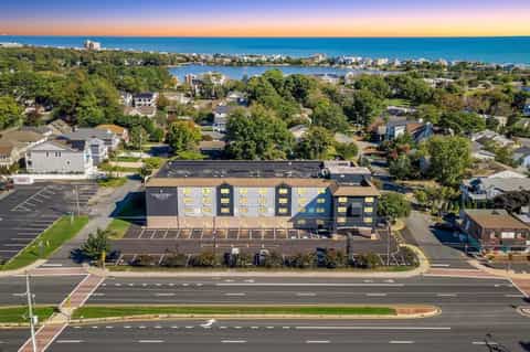 Country Inn hotel aerial view with parking lot, waterfront, trees, and coastal backdrop