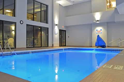 Indoor heated swimming pool with blue water, glass doors, and safety equipment