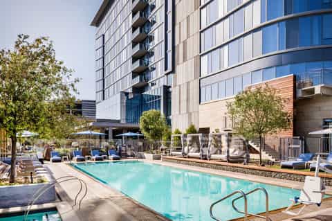 Modern hotel courtyard with turquoise swimming pool, lounge chairs, and contemporary residential building