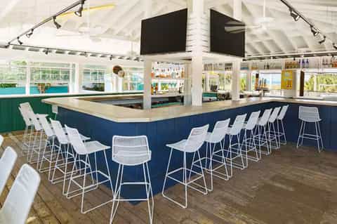 Beachfront bar with navy and white interior, high ceiling, open windows, and ocean view