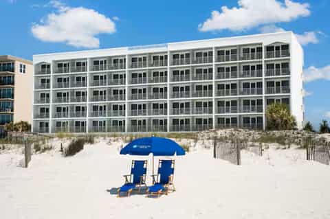 White beachfront condominium building with blue umbrellas on sandy beach