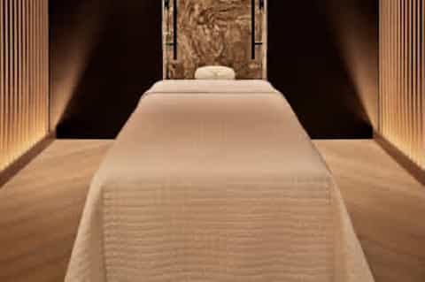 Luxury spa massage room with cream-colored table, warm lighting, and decorative wall panel