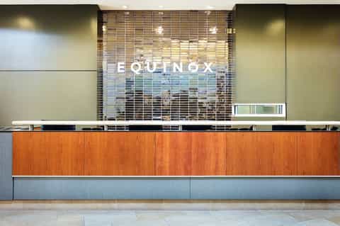 Modern hotel reception desk with wooden paneling and Equinox branding