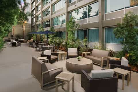 Modern resort courtyard with comfortable seating, shade umbrellas, and green landscaping