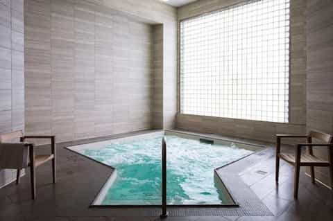 Japanese-style spa bath with natural stone surroundings and diffused natural light