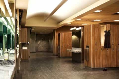 Modern spa locker room with wood cabinetry, marble sinks, and clean contemporary design