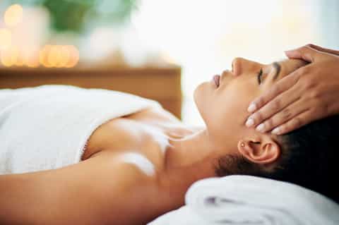 Spa treatment massage with therapist's hands on client's forehead and relaxing ambiance