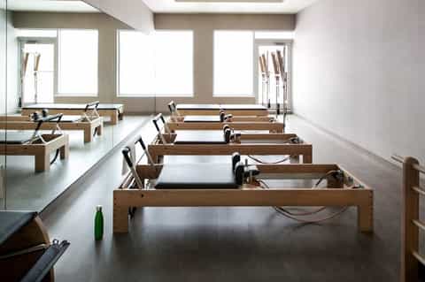 Modern spa treatment room with wooden Pilates reformer machines and natural skylight illumination