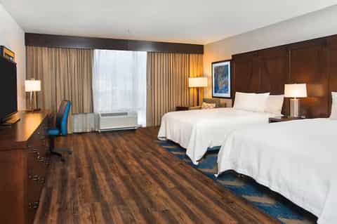 Hotel room with two queen beds, wood furniture, and city view windows