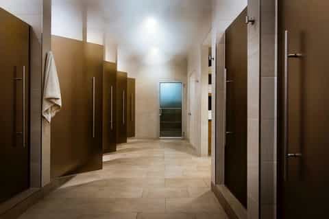 Hotel locker room hallway with individual lockers, mirrors, and neutral tile flooring