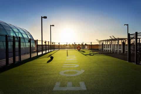 Artificial turf training field with goal areas, fencing, and floodlights at dusk