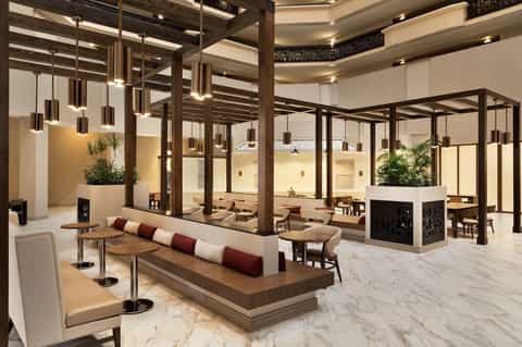 Modern hotel lobby with wood columns, pendant lighting, marble floors, and contemporary furnishings