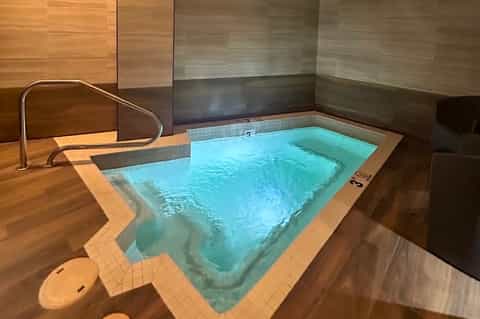 Modern Japanese-style indoor hot spring bath with light wood paneling and turquoise water