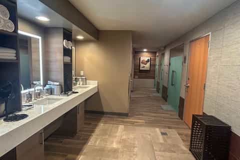 Spa facility hallway with vanity counters, multiple treatment room doors, and modern lighting