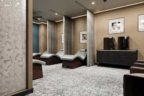 Modern spa relaxation room with dark wood loungers, white cushions, and curtained privacy dividers