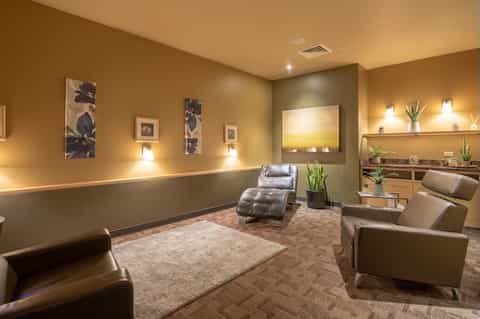 Luxurious spa relaxation room with tan and brown tones, comfortable seating, and ambient lighting