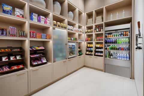 Modern hotel convenience store with shelved snacks, beverages, and refrigerated products