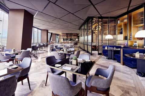 Upscale restaurant with marble floors, modern seating, and floor-to-ceiling windows