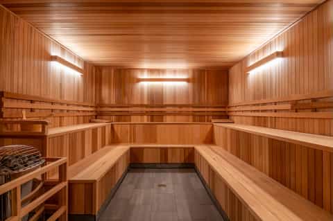 Interior of a wood-paneled sauna with tiered benches and ambient lighting throughout