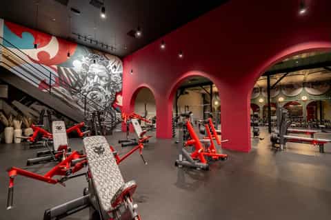 Modern red gym facility with exercise equipment and large sculptural head artwork on pink walls