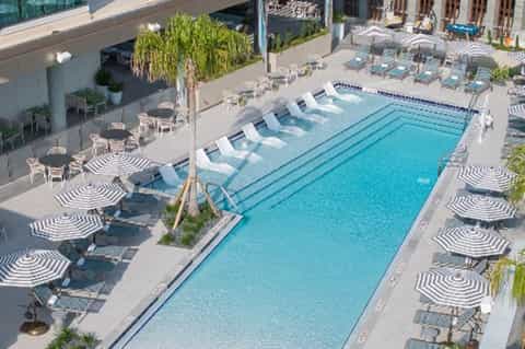 Resort lap pool surrounded by striped umbrellas, loungers, and manicured landscaping