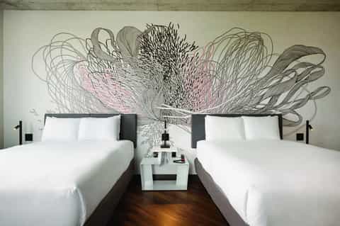 Modern hotel room with two queen beds and artistic black and pink wall mural